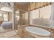 Bathroom showcasing the soaking tub, glass-enclosed shower, tile surround, and natural light through the window at 2325 W Mineral Rd, Phoenix, AZ 85041