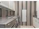 Bright laundry room with gray and white striped walls, cabinetry, countertop, and stainless steel washer and dryer at 2325 W Mineral Rd, Phoenix, AZ 85041