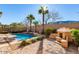 Backyard pool with water feature, lush landscaping, palm trees, an outdoor fireplace, and desert scenery at 2325 W Mineral Rd, Phoenix, AZ 85041