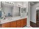 Bright bathroom with double sinks, wooden cabinets and a large mirror at 41105 N Prestancia Way, Anthem, AZ 85086