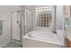Elegant bathroom featuring a soaking tub next to a glass shower, with a window for natural light at 41105 N Prestancia Way, Anthem, AZ 85086