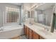 Bright bathroom featuring a soaking tub beneath a window and a glass-enclosed shower at 41105 N Prestancia Way, Anthem, AZ 85086