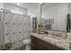 Stylish bathroom with a granite countertop vanity, decorative mirror and a shower with a patterned curtain at 5831 N 196Th Ln, Litchfield Park, AZ 85340