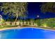 Relaxing backyard pool with ambient lighting, lounge chair, and well-maintained landscaping under a large tree at 7278 E Echo Ln, Scottsdale, AZ 85258