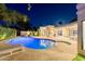 Exterior night shot showcasing a pool with inset spa, lounge chairs, an outdoor grilling station, and covered patio at 7278 E Echo Ln, Scottsdale, AZ 85258