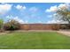 Spacious backyard with lush artificial grass, a brick retaining wall, and desert landscaping at 9743 E Torino Ave, Mesa, AZ 85212