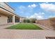 Landscaped backyard with artificial grass, mature bushes, brick pavers, and a covered patio at 9743 E Torino Ave, Mesa, AZ 85212