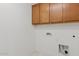 This laundry room offers wood upper cabinets, tile flooring and washer dryer hookups at 9743 E Torino Ave, Mesa, AZ 85212