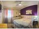 Comfortable bedroom featuring a floral comforter and a bright purple accent wall at 10928 W Kaler Dr, Glendale, AZ 85307