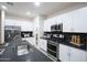 Modern kitchen featuring white cabinetry, stainless steel appliances, and a black tile backsplash at 13195 N 145Th Ln, Surprise, AZ 85379