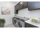 Functional laundry room with front load washer and dryer, overhead cabinets and ample counter space at 13914 E Barwick Dr, Scottsdale, AZ 85262