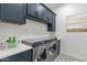 Laundry room features a modern washer and dryer with dark blue cabinets and quartz countertops at 13929 E Barwick Dr, Scottsdale, AZ 85262