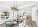 Open-concept dining room featuring a glass-top table, stylish chandelier, and views into the modern kitchen and living area at 13930 E Barwick Dr, Scottsdale, AZ 85262