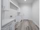 Bright laundry room with white cabinets, quartz counters, stainless faucet and wood-look tile floors at 14328 E Peak View Rd, Scottsdale, AZ 85262