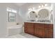 Bathroom featuring a tub, double sinks, and granite countertops at 15816 W Amelia Dr, Goodyear, AZ 85395