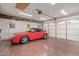 Clean garage featuring epoxy floors, white cabinets, a red sports car, and a bright overhead light at 15816 W Amelia Dr, Goodyear, AZ 85395