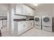 Laundry room featuring white cabinets, granite counters, tile flooring, and front loading washer and dryer at 15816 W Amelia Dr, Goodyear, AZ 85395