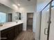 Bright bathroom featuring double vanity, wood-look floors, glass shower, and walk-in closet access at 17547 W Lupine Ave, Goodyear, AZ 85338