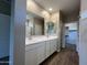 Bathroom features a dual sink vanity, modern mirrors, and wood look floors at 17553 W Lupine Ave, Goodyear, AZ 85338