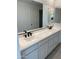 Modern bathroom with a double sink vanity featuring white cabinets and black faucets beneath a large mirror at 18035 W Vogel Ave, Goodyear, AZ 85338