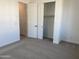 Cozy bedroom featuring neutral carpet, white walls, and an adjacent closet with sliding doors at 18035 W Vogel Ave, Goodyear, AZ 85338