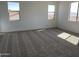 Bright bedroom featuring neutral carpet, white walls, and well-lit with multiple windows at 18035 W Vogel Ave, Goodyear, AZ 85338