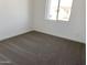 Well-lit bedroom with neutral carpet, white walls, and a window with a view of the neighborhood at 18035 W Vogel Ave, Goodyear, AZ 85338