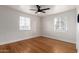 Bright bedroom featuring a ceiling fan, two windows, and hardwood floors at 2256 W Ella St, Mesa, AZ 85201