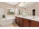 Bright bathroom with double sinks, a soaking tub, and a separate shower, perfect for relaxation and comfort at 3044 E Trigger Way, Gilbert, AZ 85297