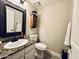 Neutral toned half bathroom with granite countertop, decorative mirror, and a wood storage cabinet at 41 S Honeysuckle Ln, Gilbert, AZ 85296