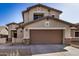 Two-story home showing a brown garage door, tan stucco, and stone veneer accents at 5313 W Jessica Ln Ln, Laveen, AZ 85339