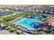 An aerial view shows a community pool area, complete with palm trees, waterslides, and lounge seating in a luxury neighborhood at 5431 S Canyon Rim --, Mesa, AZ 85212