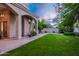 Manicured backyard featuring lush green lawn, gravel accents, shade trees, and a covered patio at 6132 E Yucca St, Scottsdale, AZ 85254