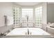 Large soaking tub set below a bay window of glass blocks, inviting natural light at 6132 E Yucca St, Scottsdale, AZ 85254