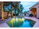 A shimmering pool and spa surrounded by mature landscaping and trees adorned with fairy lights at 6132 E Yucca St, Scottsdale, AZ 85254