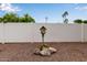 Gravel backyard featuring a decorative birdhouse with accent rocks and a white fence surround at 641 N 61St Pl, Mesa, AZ 85205