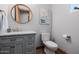 Stylish bathroom with a gray vanity, marble countertop, oval mirror, and modern toilet with wood look flooring at 7482 S Mccormick Way, Queen Creek, AZ 85142