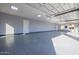 Clean, empty, bright garage with epoxy flooring, several lights, and an access door at 7482 S Mccormick Way, Queen Creek, AZ 85142