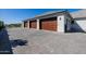 Multiple garages featuring dark wood doors, interlocking brick driveway and manicured landscaping at 7482 S Mccormick Way, Queen Creek, AZ 85142