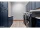 Modern laundry room with navy cabinets, quartz countertops, tile floors, and high-end washer and dryer units at 7482 S Mccormick Way, Queen Creek, AZ 85142