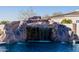 A serene pool scene featuring a multi-tiered rock waterfall feature and lush, cool blue water at 7482 S Mccormick Way, Queen Creek, AZ 85142