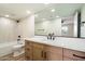 Modern bathroom with wood cabinetry, dual sinks, a framed mirror, and a shower/tub combo at 8377 E Indian School Rd, Scottsdale, AZ 85251