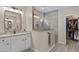 Bright bathroom featuring granite counters, white cabinets, a rectangular mirror, and a glass shower stall at 10256 W Appaloosa Trl, Casa Grande, AZ 85194