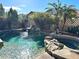 Relaxing backyard pool area featuring a rock waterfall, lush greenery, and a tall palm tree for shade at 1131 W Sierra Madre Ave, Gilbert, AZ 85233