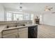 Bright kitchen featuring a stainless steel sink, black dishwasher, and view of the living area with fireplace at 126 S Rita Ln, Chandler, AZ 85226