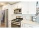 Well-lit kitchen with stainless steel appliances, quartz countertops and white cabinetry at 14266 N 2Nd Ave, Phoenix, AZ 85023