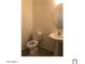 A simple half-bathroom featuring a white toilet and a pedestal sink with a round mirror at 1709 W Pollack St, Phoenix, AZ 85041