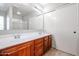 This spacious bathroom offers dual sinks, cherry wood cabinetry, and a large mirror at 17474 W Acapulco Ln, Surprise, AZ 85388