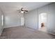 This bedroom features neutral walls, carpet, a ceiling fan, and access to the attached bathroom at 17474 W Acapulco Ln, Surprise, AZ 85388