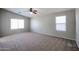 This spacious bedroom features neutral walls, carpet, a ceiling fan, and two bright, sunlit windows at 17474 W Acapulco Ln, Surprise, AZ 85388